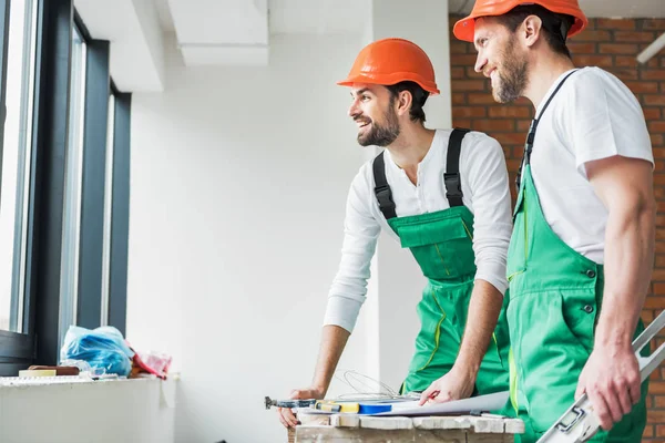 Jolly constructores sonrientes mirando a un lado — Foto de Stock