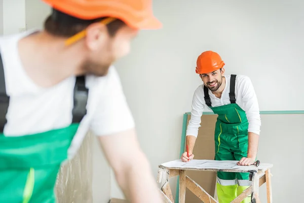 Alegre constructor sonriente mantener la pluma — Foto de Stock