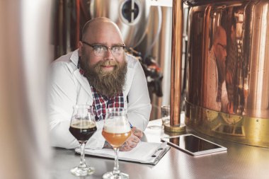 Neşeli sakallı adam bira fabrikasında poz