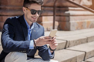 Mutlu gülümseyen erkek kişi telefonla yazarak