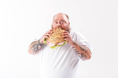 Büyük hamburger ısırma kalın adam açlıktan