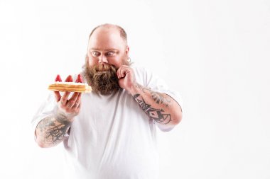Hungry male fatso looking at cake with desire clipart