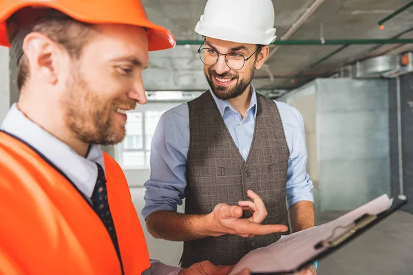 Hilarious contractor standing beside colleague — Stock Photo, Image