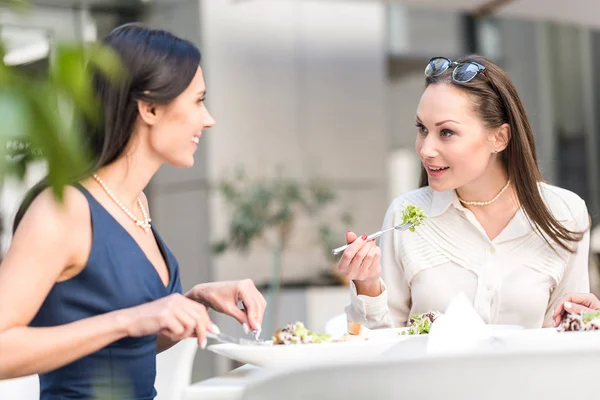 Улыбающиеся девушки едят салат за столом — стоковое фото