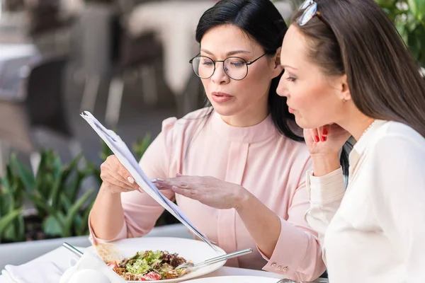 Спокойные женщины выбирают блюдо за столом — стоковое фото