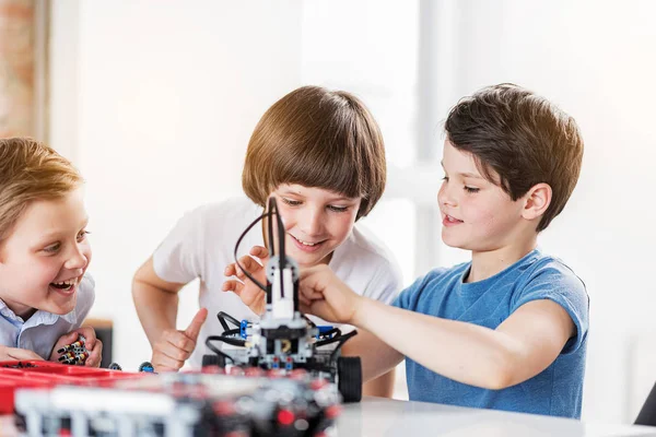 Niños sonrientes interesados haciendo juguete técnico — Foto de Stock