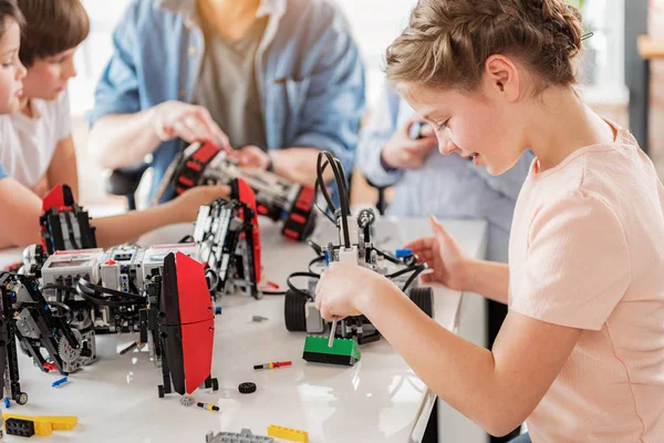 Concentrated smiling girl creating technical toy — Stock Photo, Image