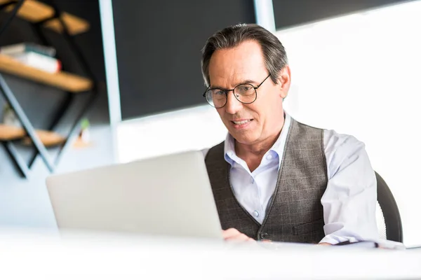 Hombre mayor positivo sentado en la mesa — Foto de Stock