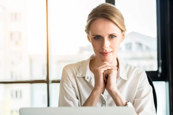 Charmiga positiv tjej sitter vid bord med liten leende — Stockfoto