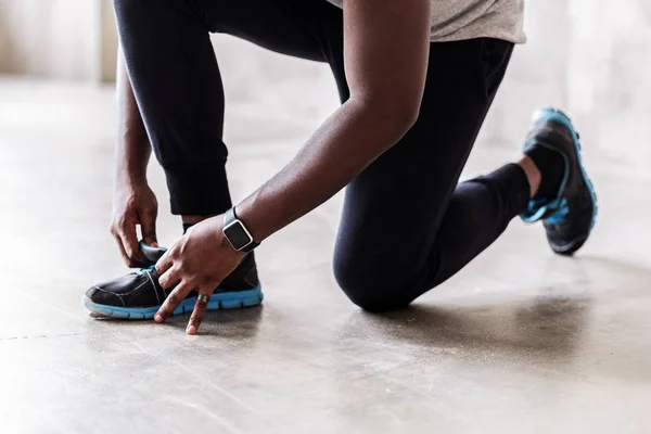 Joven atleta muscular arreglando su zapato de entrenamiento —  Fotos de Stock