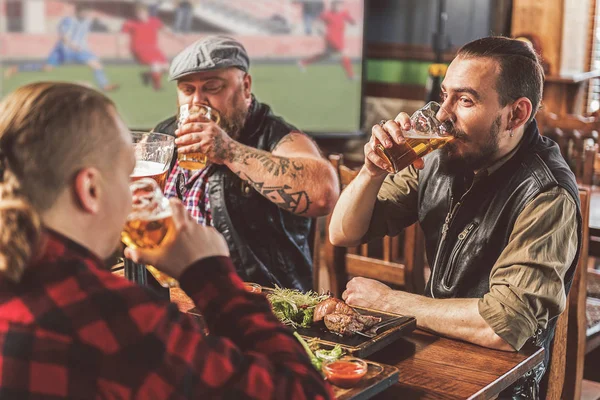Drie bebaarde jongens genieten van bier in de kroeg — Stockfoto