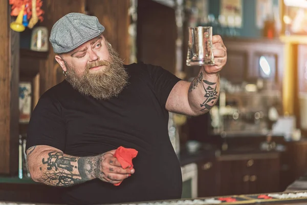 Tlustý barman pilně utírání pivní sklo — Stock fotografie