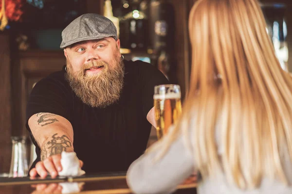 Barman gordo barbudo alegre mirando al cliente juguetonamente — Foto de Stock