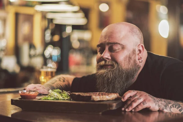 Masculino obeso saboreando carne a la parrilla en el pub — Foto de Stock