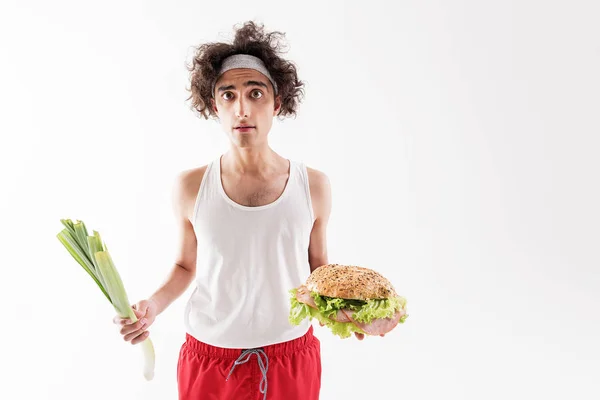 Slim guy choosing between healthy and unhealthy food — Stock Photo, Image