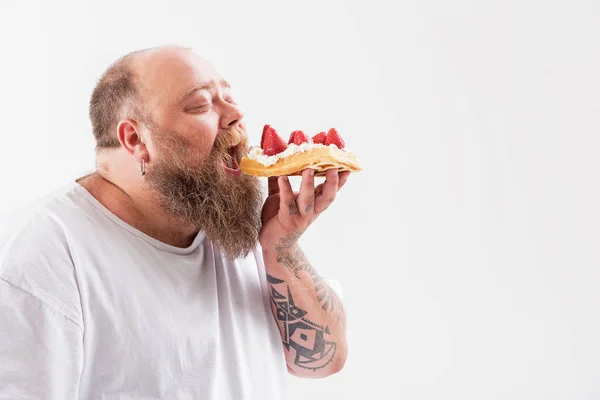Uomo di spessore affamato mordere grande dessert cremoso — Foto Stock