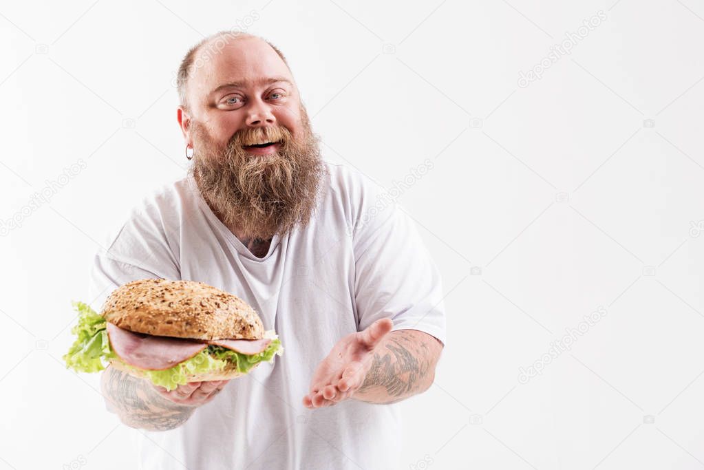 Confident thick guy presenting unhealthy hamburger