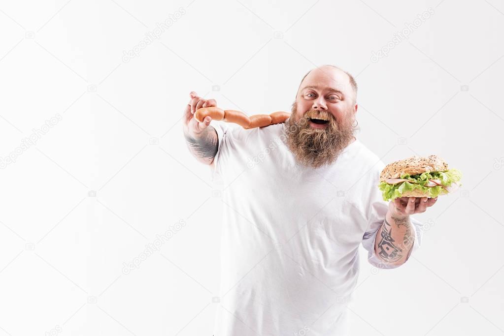 Glad bearded fat man enjoying unhealthy food