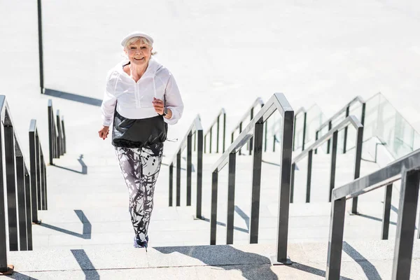 Веселая пожилая леди бежит по бетонным ступенькам на улице — стоковое фото