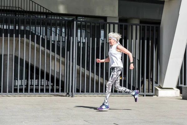 Ernstige bejaarde dame uit te oefenen buiten in de buurt van metalen reling — Stockfoto