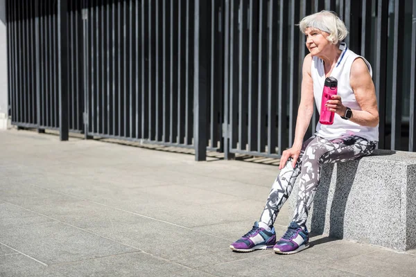 Задумчивая пожилая женщина отдыхает во время занятий на открытом воздухе — стоковое фото