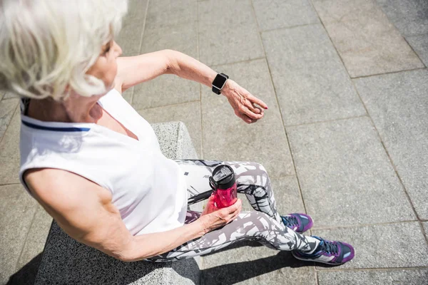 Пожилая дама расслабляется после спортивных мероприятий на улице здания — стоковое фото