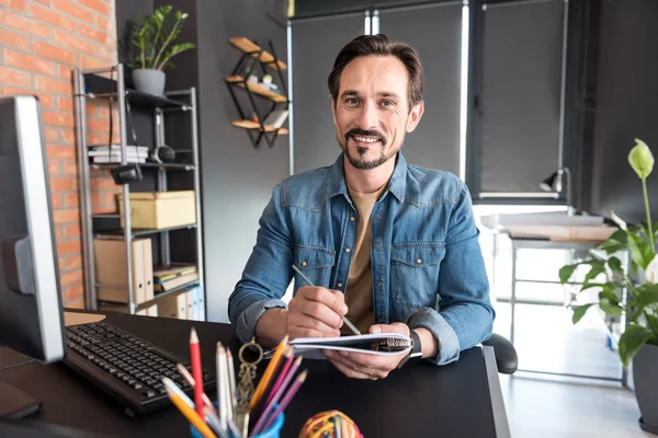 Hombre sonriente atento que hace su trabajo en la oficina — Foto de Stock