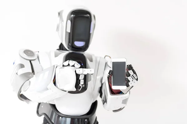 Приятный робот стоит со смартфоном — стоковое фото