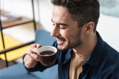 Sıcak bir içecek zevk alarak neşeli yakışıklı adam