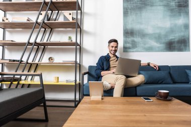 Mutlu genç adam evde bilgisayar yolu ile çalışma