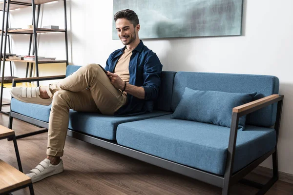 Oturma odasında rahatlatıcı sakallı neşeli genç adam