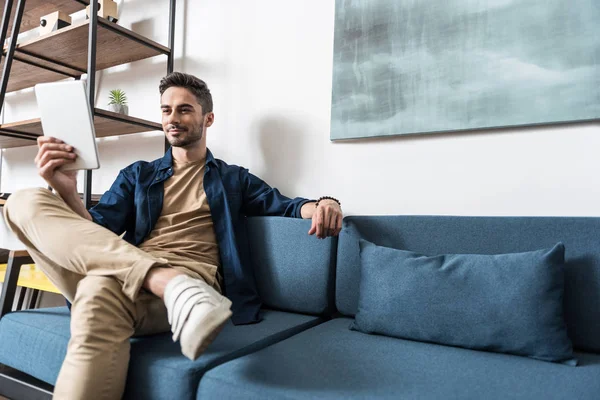 Homem bonito alegre que descansa com e-book — Fotografia de Stock