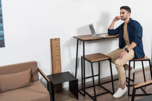 Evde çalışan dizüstü bilgisayar yolu ile düşünceli genç işadamı