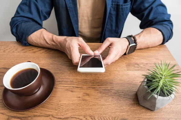 Genç adam mesaj yolu ile smartphone mutfak masasında