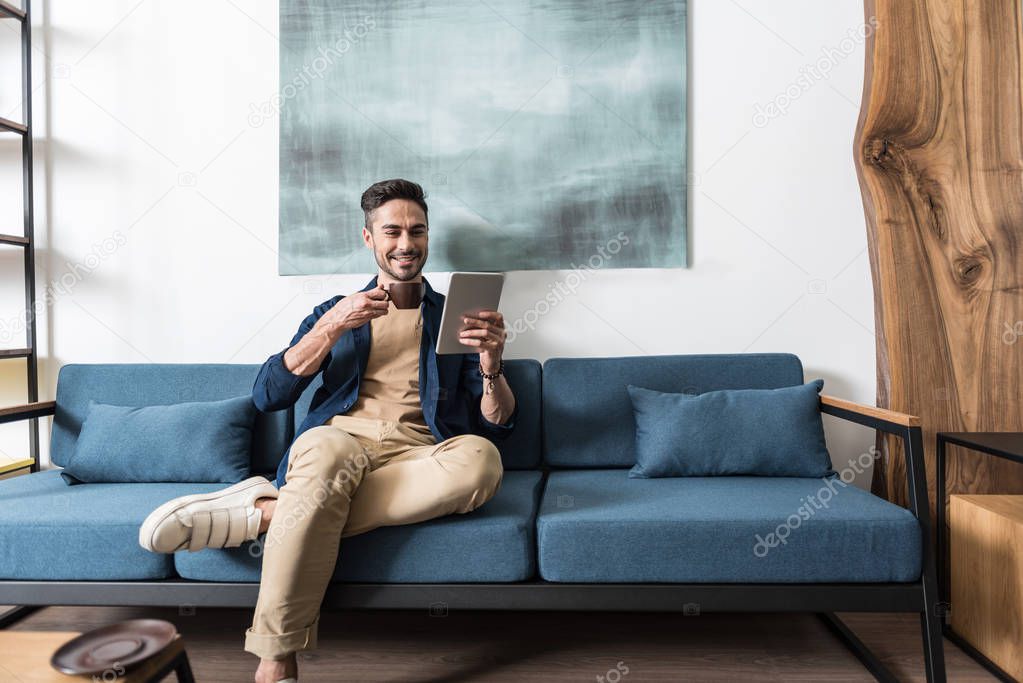 Cheery bearded guy having relax time at his living room