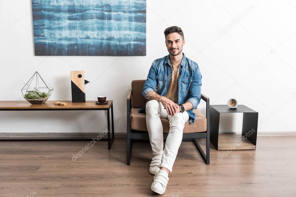 Cheerful youthful guy relaxing in living room