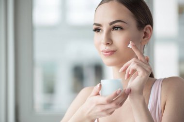 Mutlu genç kadın yüz kozmetik kullanma