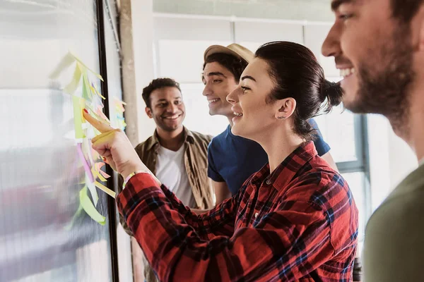 Equipo alegre creando nuevas ideas cerca de tablero de cristal — Foto de Stock