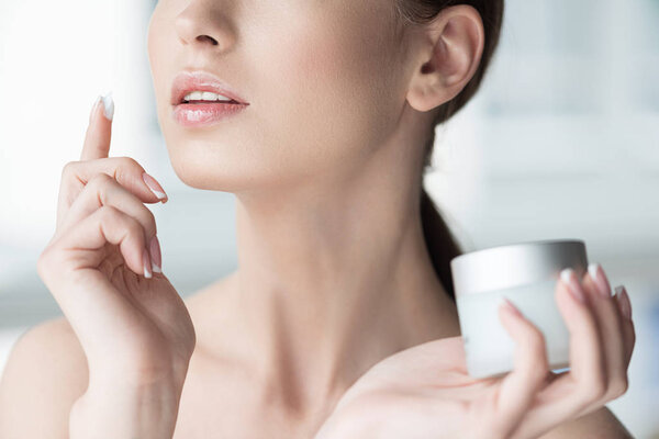 Youthful lady putting cosmetics on face