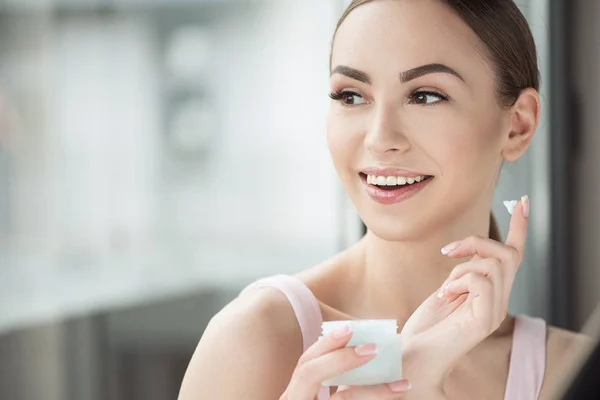 Menina feliz bonita usando cosméticos para a pele — Fotografia de Stock