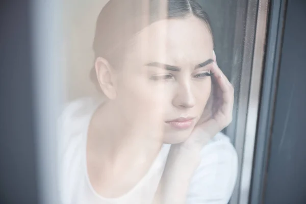 Triste jovem mulher assistindo mau tempo em casa — Fotografia de Stock