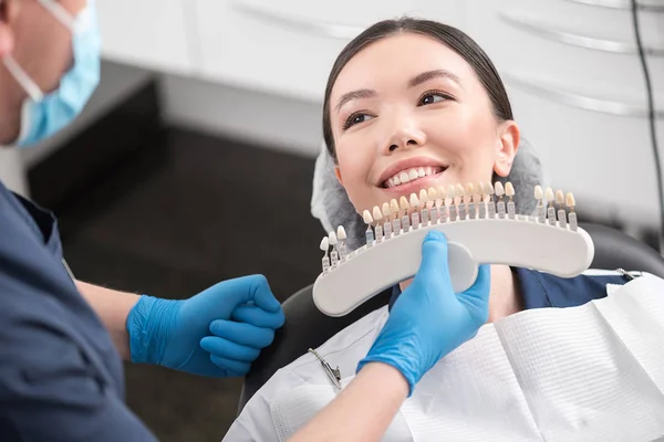 Odontólogo seleccionando corona dental al cliente radiante —  Fotos de Stock