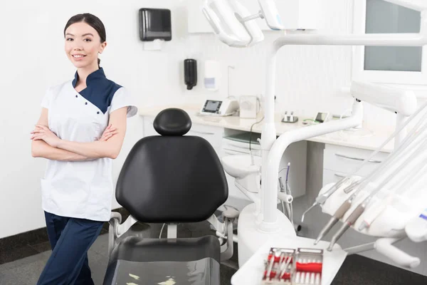Dentista feliz de pé perto de instrumentos no quarto — Fotografia de Stock