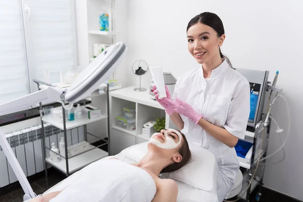 Cosmetólogo alegre está trabajando con el cliente en el salón de spa — Foto de Stock