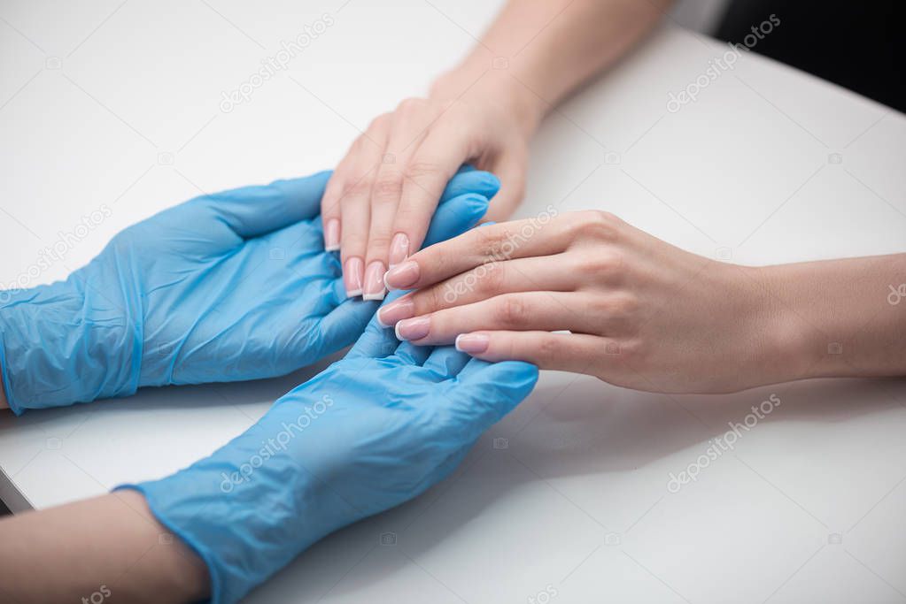 Beautician is checking cuticles of girl