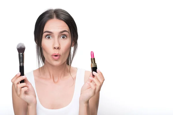 Überraschte junge Frau zeigt Lippenstift und Pinsel — Stockfoto