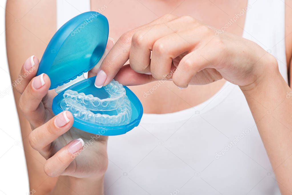 Young woman holding cover with clear aligners