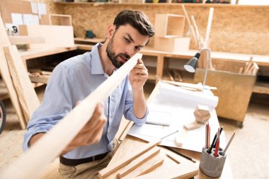 Konsantre sakallı genç woodworker masasında iş parçası kadar kontrol