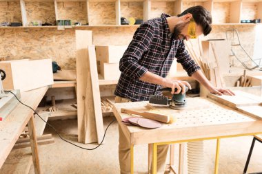 Neşeli woodworker aletle yorucu sırasında masanın üzerine eğilerek