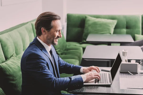 Joyful businessman using computer in internet cafe